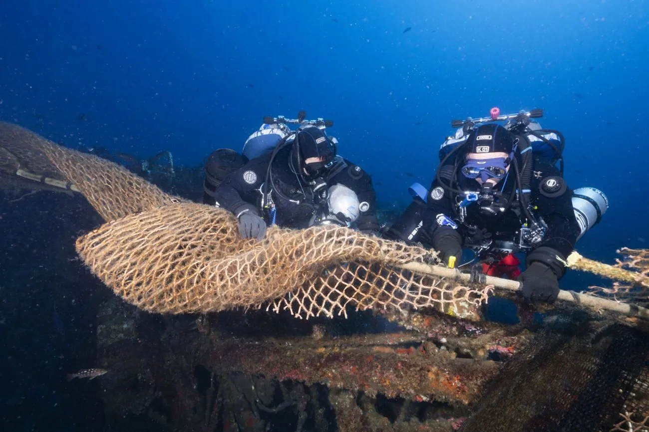Trawl netting draped over the Midnight Hour wreck as divers begin removal